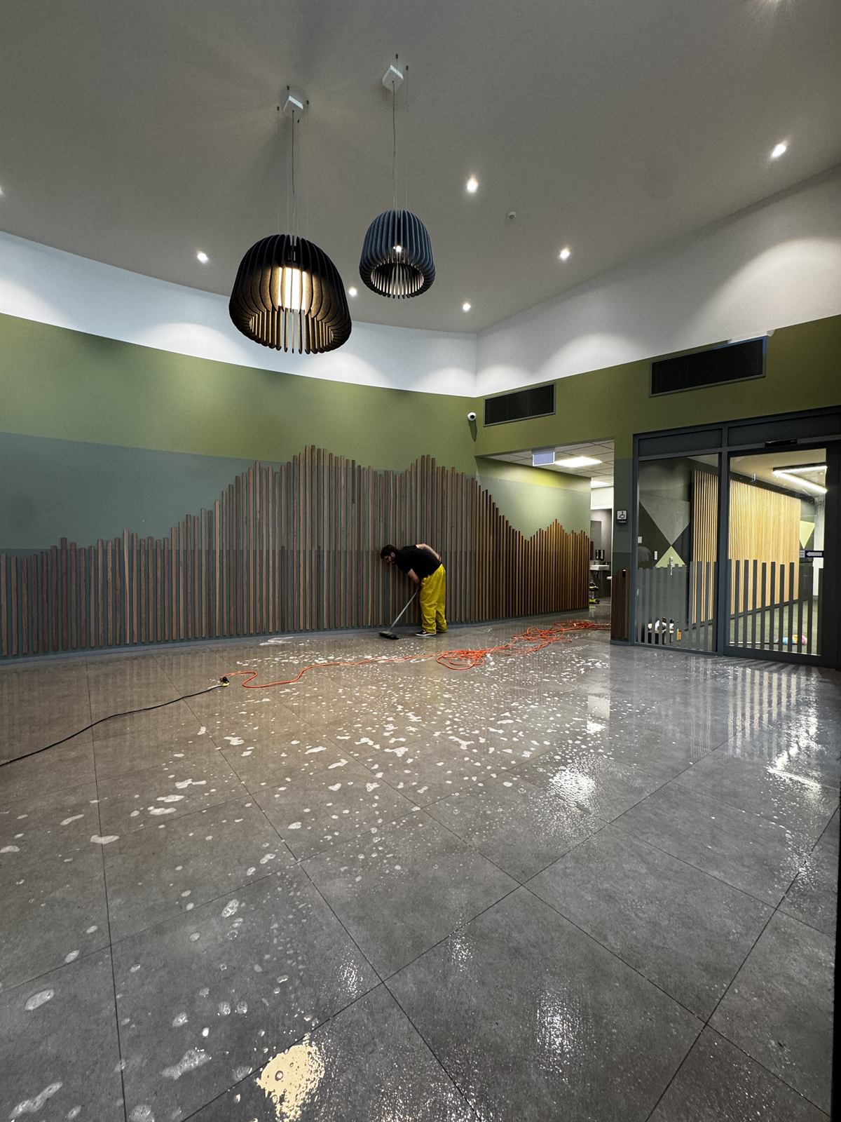 Mid-deep-clean of a polished concrete floor in a high-ceilinged commercial space